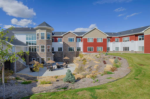 A modern residential building with landscaped surroundings under a clear blue sky.
