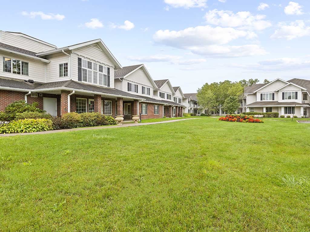 A row of suburban townhouses with a well-maintained lawn in the foreground.