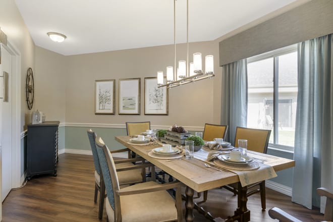 A stylish dining room with a wooden table, cushioned chairs, and elegant lighting.