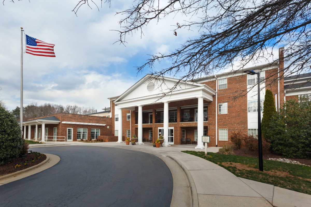 A large brick building with white columns and a curved driveway at the entrance.