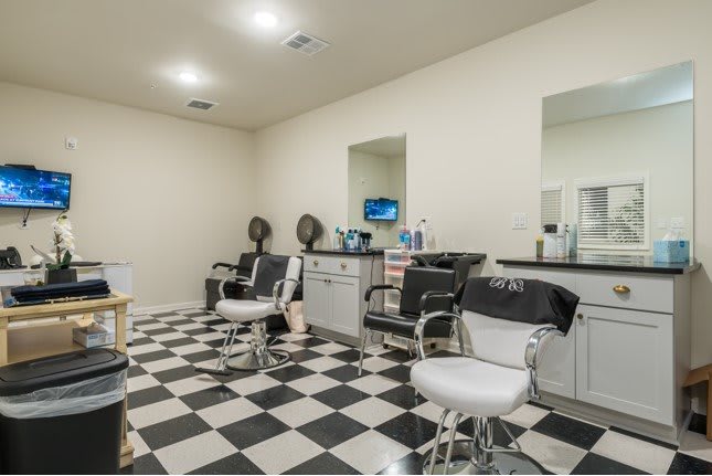 A tidy barbershop with checkered flooring and several barber chairs ready for clients.