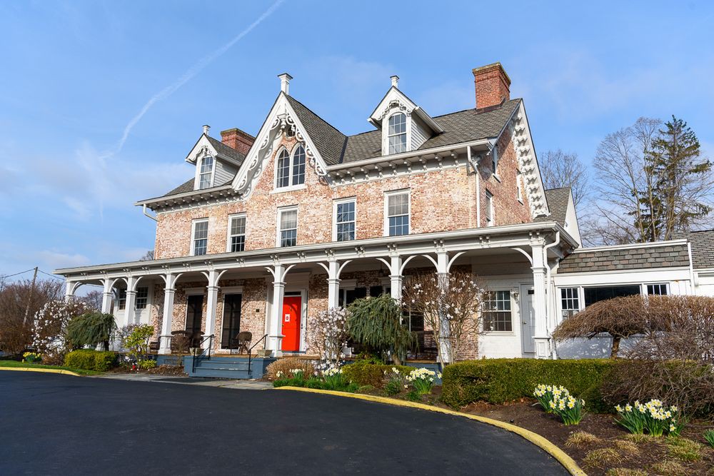 A historic Victorian-style house with a brick exterior and a spacious porch.