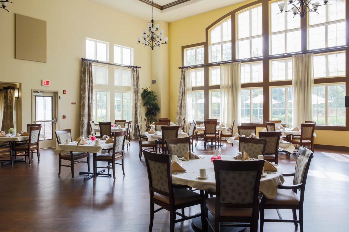 An elegant dining room with large windows and neatly arranged tables.