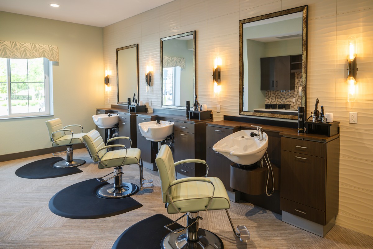 A modern hair salon interior featuring styling chairs, mirrors, and washing sinks.