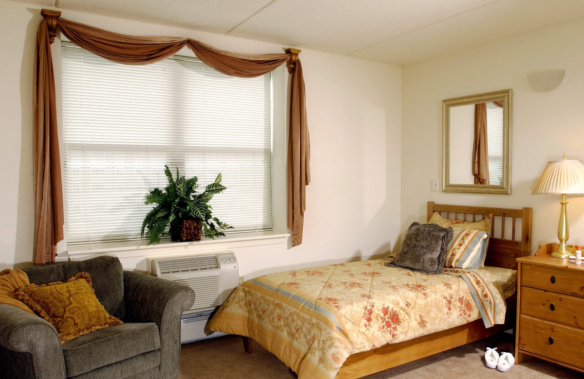 A cozy bedroom with a single bed and an armchair by the window.