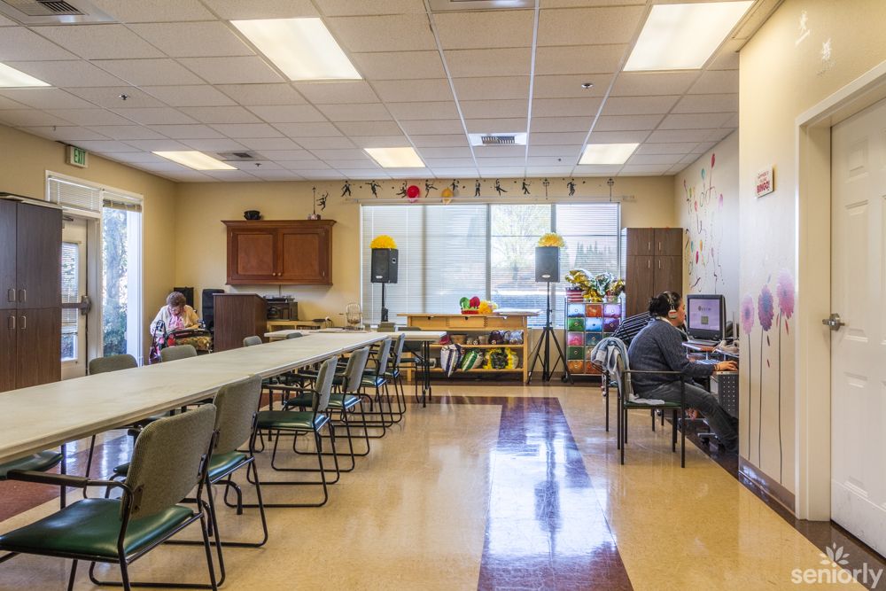 A classroom with desks, chairs, and computers, with people working inside.