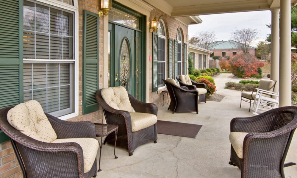 A welcoming patio with comfortable rattan chairs and a green door entrance.
