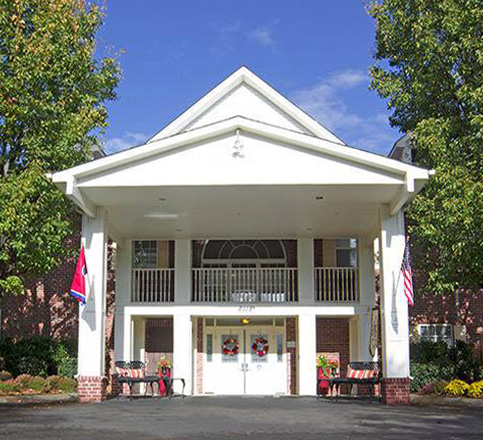 A welcoming hotel entrance with a classic design and surrounding greenery.