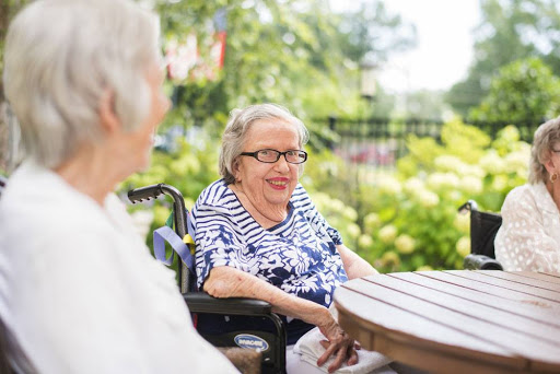 Two elderly women enjoying a sunny day outdoors, sharing smiles and conversation.