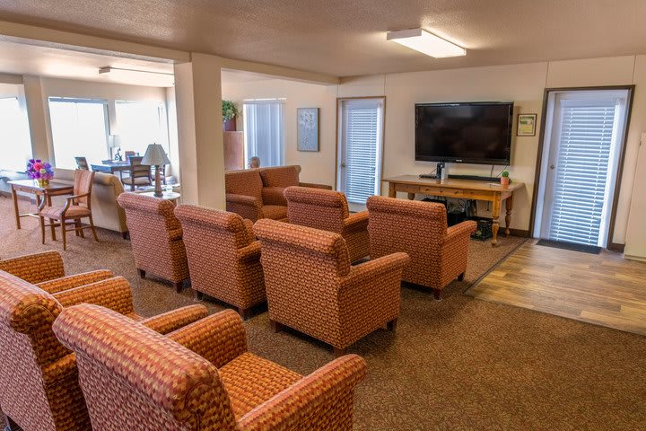 A cozy communal living room with multiple armchairs facing a television.