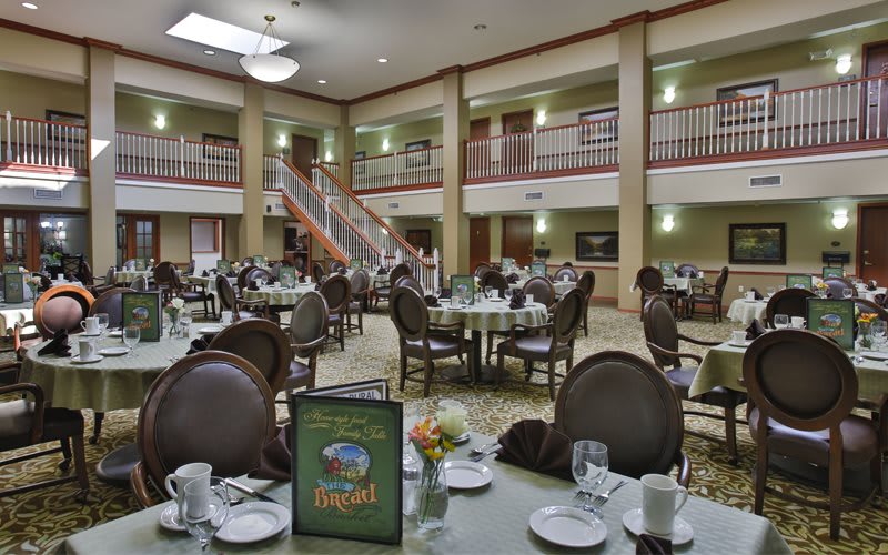 An elegantly set dining area with round tables and chairs, ready for guests.