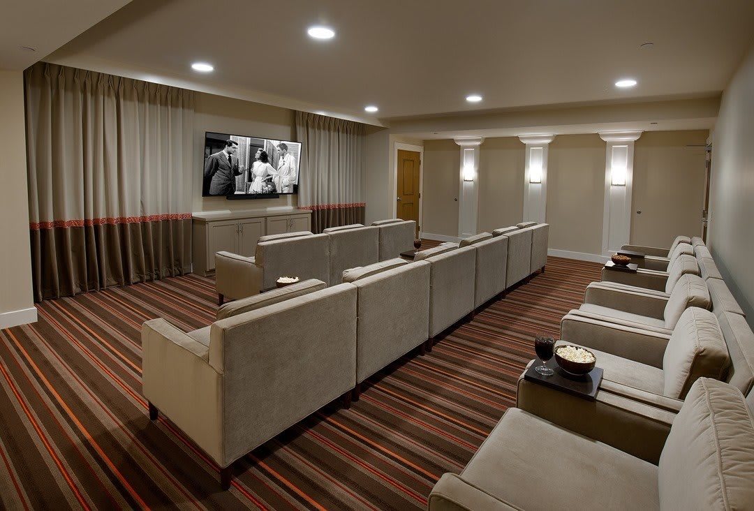 A modern home theater with luxury seating and a large television.