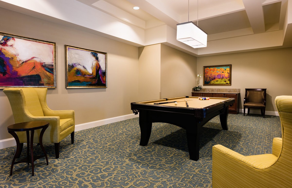 A stylish recreation room featuring a pool table, modern artwork, and comfortable seating.