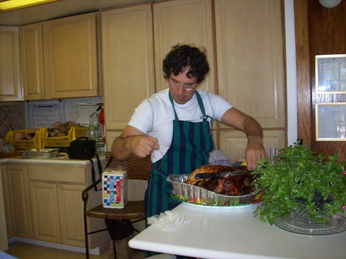 A person in a kitchen carving a roasted turkey.