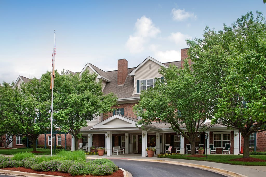 A scenic view of a traditional multi-story building surrounded by trees with a driveway leading to the entrance.