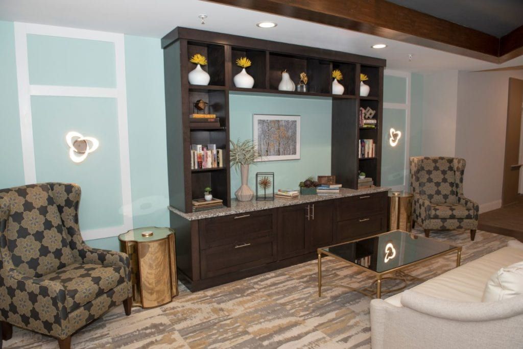 A modern living room with a stylish entertainment unit, featuring shelves decorated with vases and books, surrounded by comfortable seating.