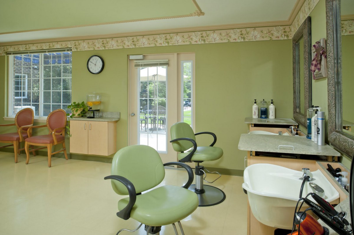 A modern and stylish hair salon interior with green chairs and bright lighting.
