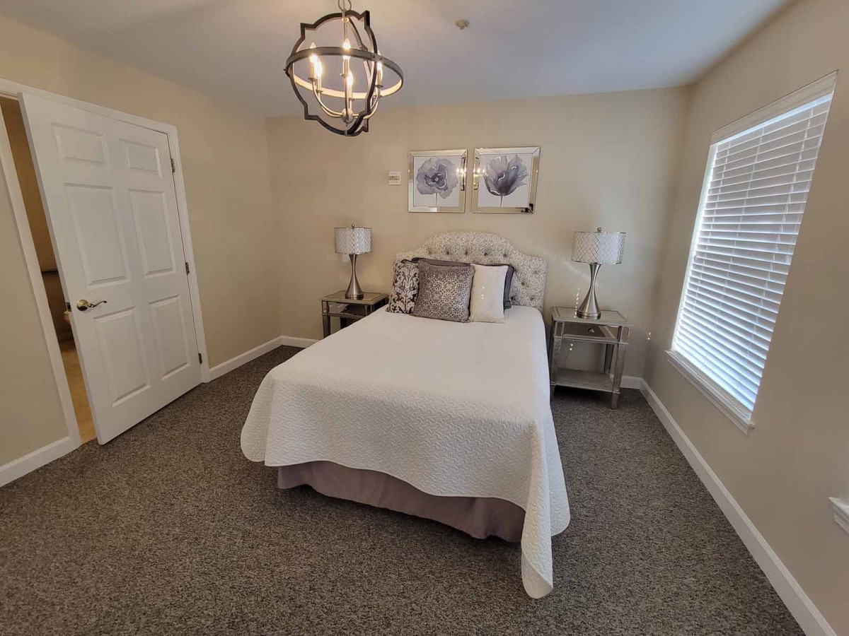 A cozy, minimalist bedroom with a bed and bedside tables under soft lighting.