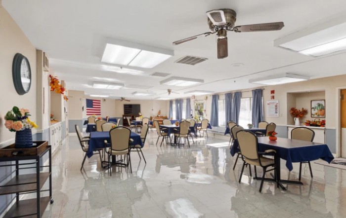 A community dining area with tables and chairs, featuring a ceiling fan and American flag.