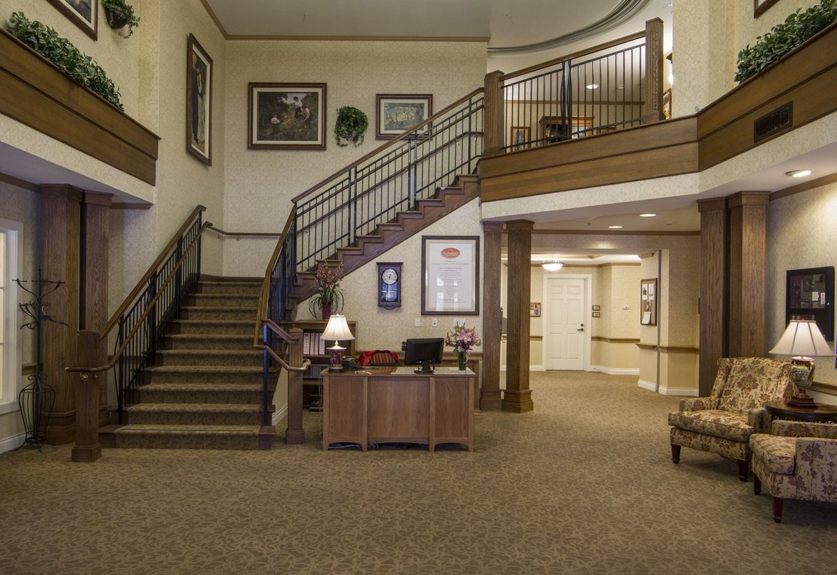 A spacious lobby with a central staircase and a reception desk.