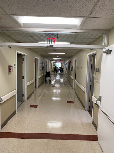 A view down a hospital hallway with lit ceiling and closed doors on either side.