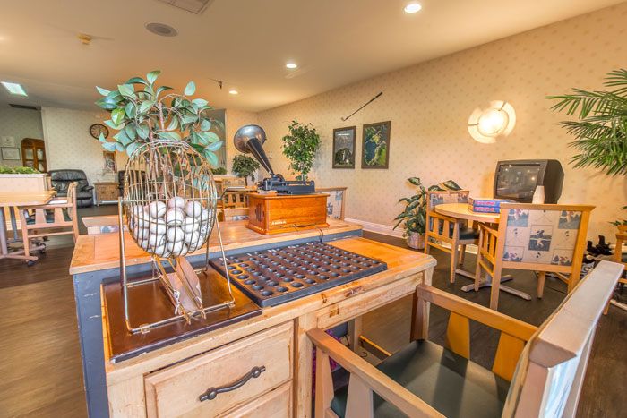 A cozy office space featuring wooden furniture, decorative plants, and framed artwork on the walls.