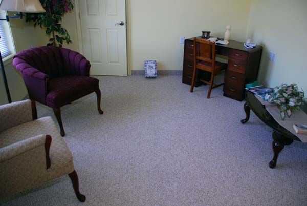 An office room with chairs, a desk, and carpeted flooring.