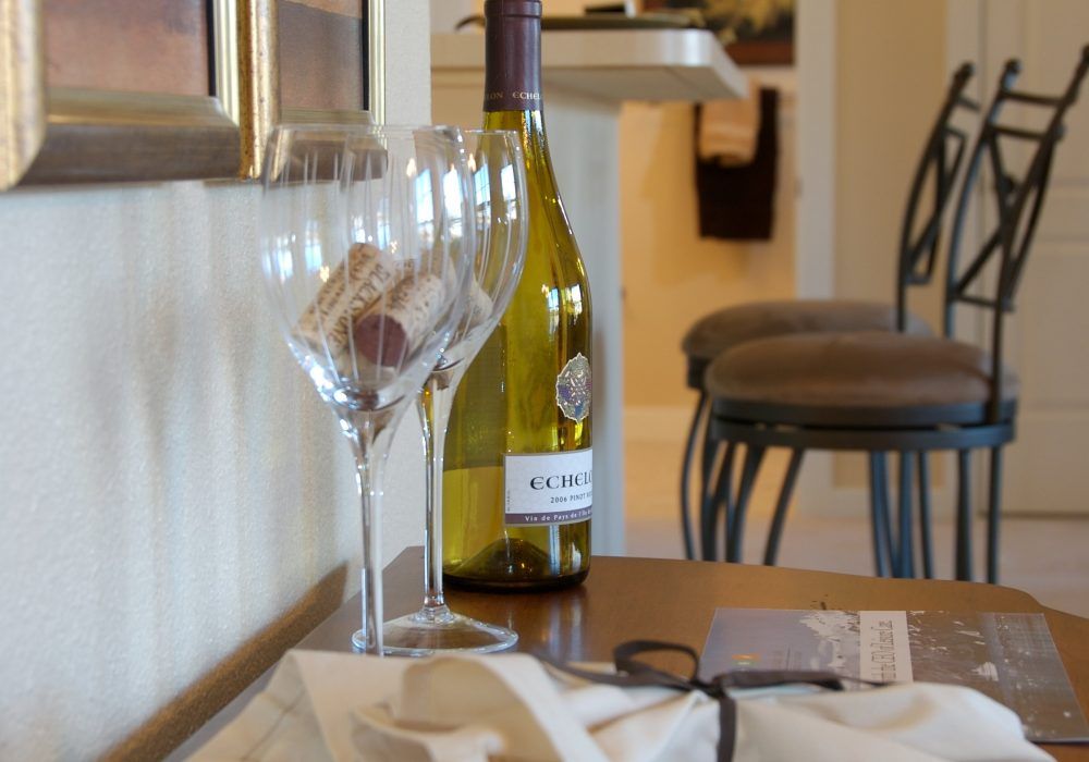 A cozy kitchen scene with a bottle of wine and wine glasses on the table.