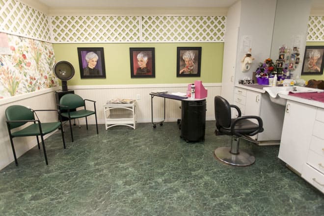 An interior view of a hair salon with chairs, a styling station, and wall art.