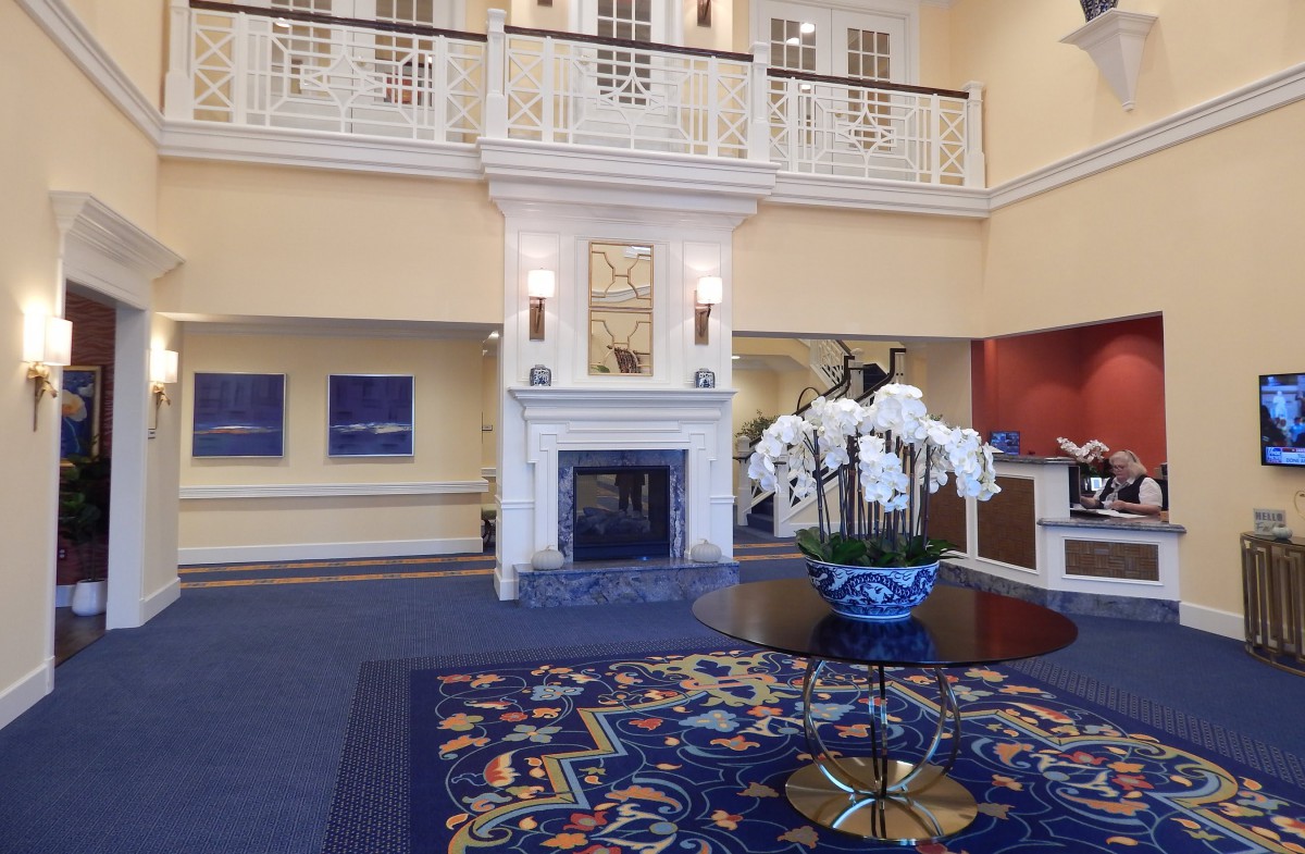 A stylish hotel lobby with a central table featuring an orchid arrangement and a grand fireplace.