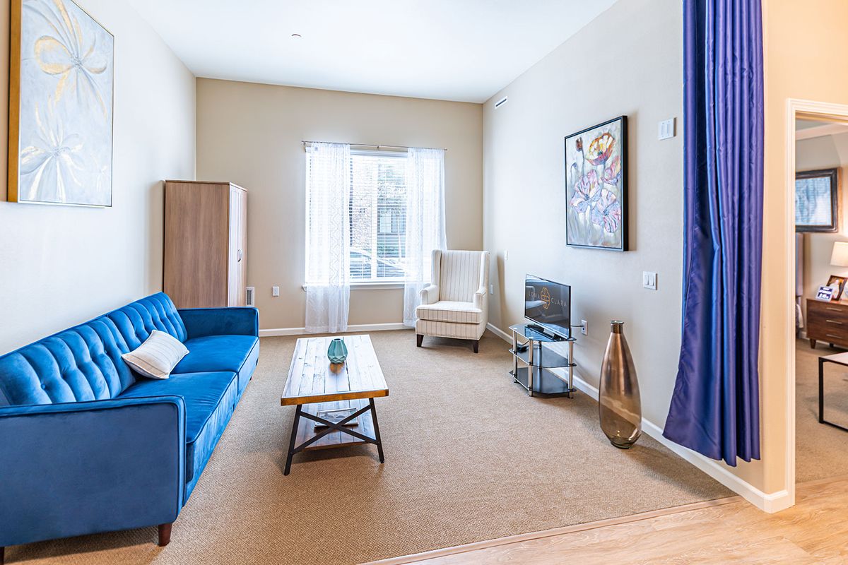 A well-lit living room with a blue sofa, coffee table, and elegant decor.