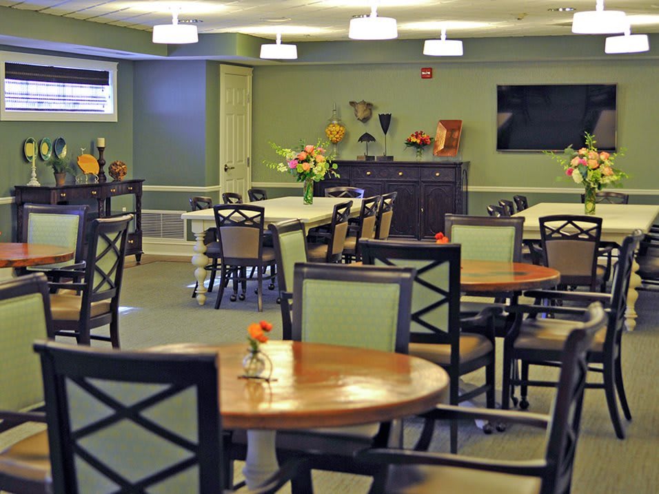 A well-lit dining room with neatly arranged tables and chairs, featuring decorative elements on the walls.