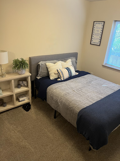 A cozy and neatly arranged bedroom featuring a bed, decorative pillows, and a stylish shelf.