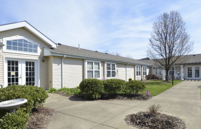 A row of suburban residential homes with well-maintained landscaping and a clear sky.