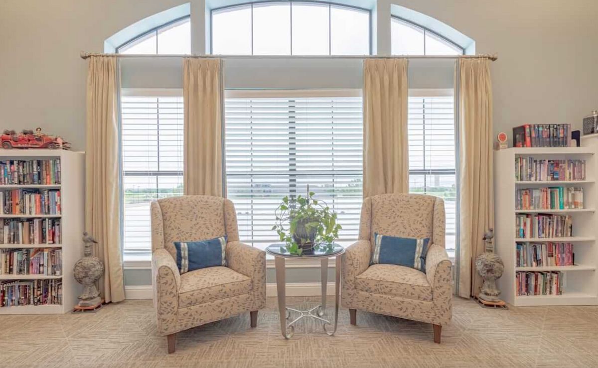 A cozy living room setup with two armchairs and a table in front of large windows.