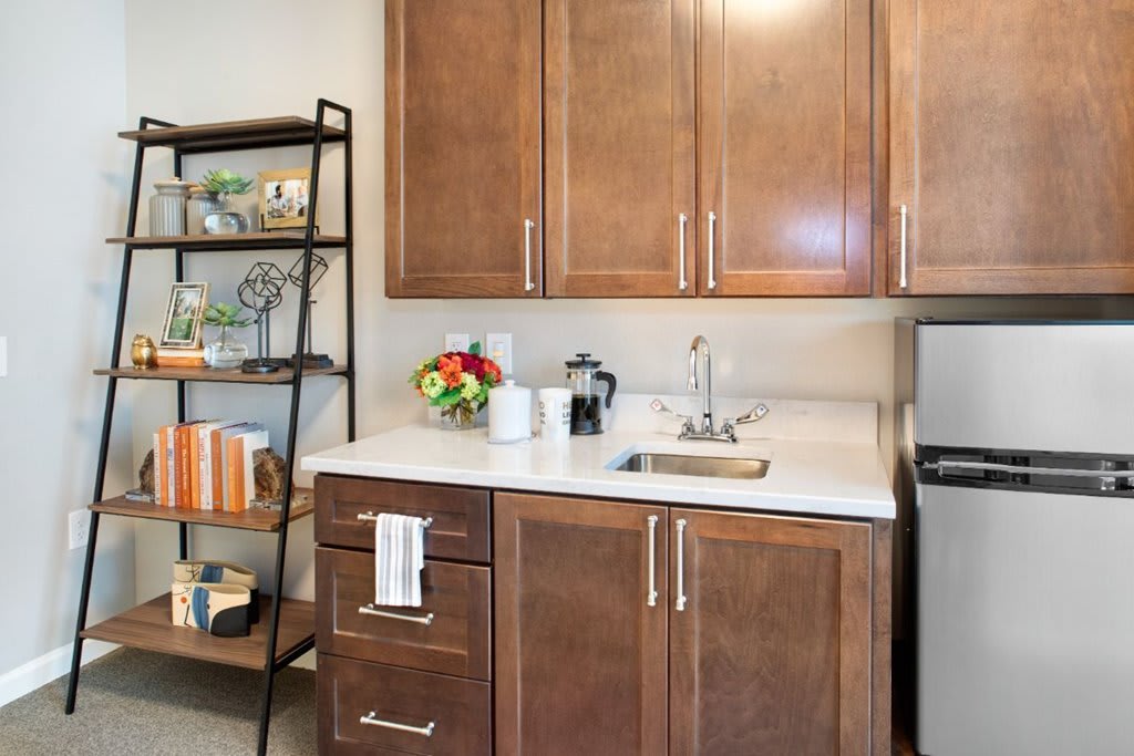 A compact kitchen area with wooden cabinets, a countertop with a sink, and shelves for storage.