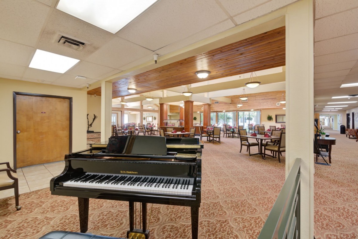A spacious community lounge with a grand piano and ample seating.