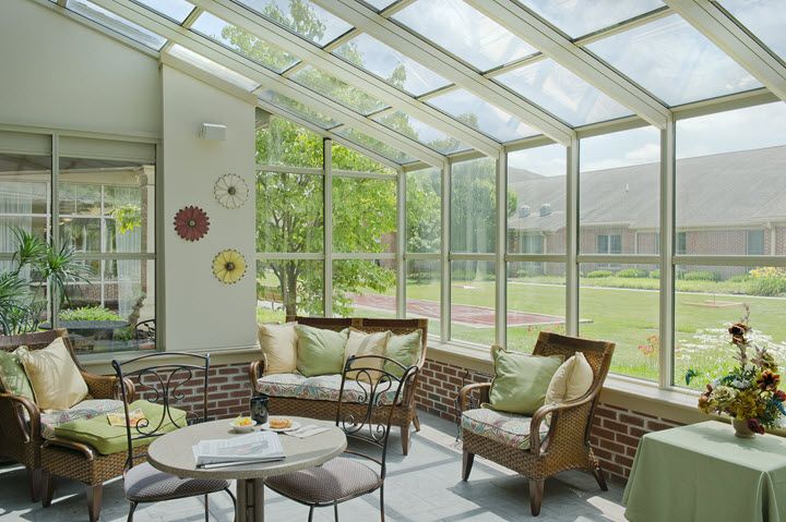 A cozy sunroom with large glass windows, comfortable seating, and ample natural light.
