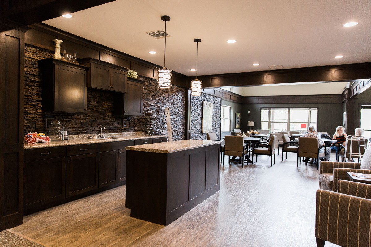 A modern kitchen and dining area with an open floor plan, featuring dark cabinets and stylish pendant lights.