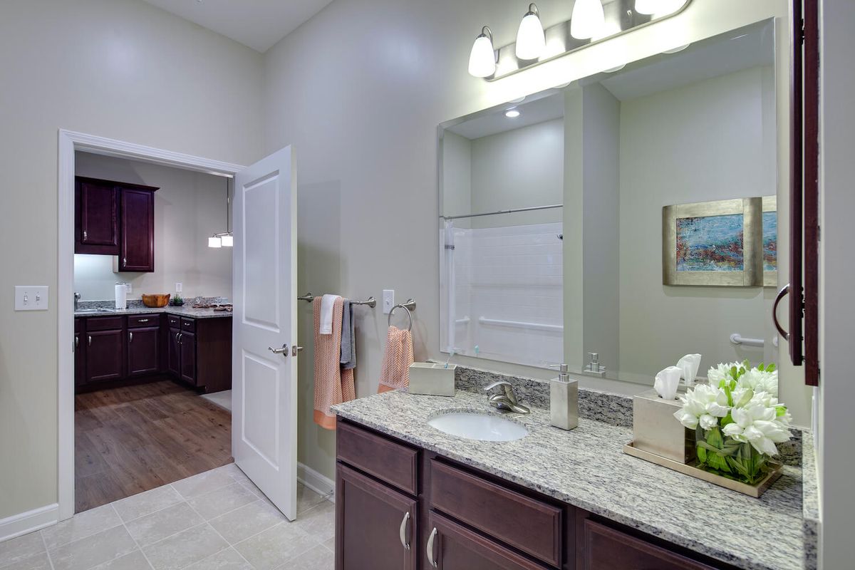 A modern bathroom with a granite countertop, mirror, and elegant lighting.