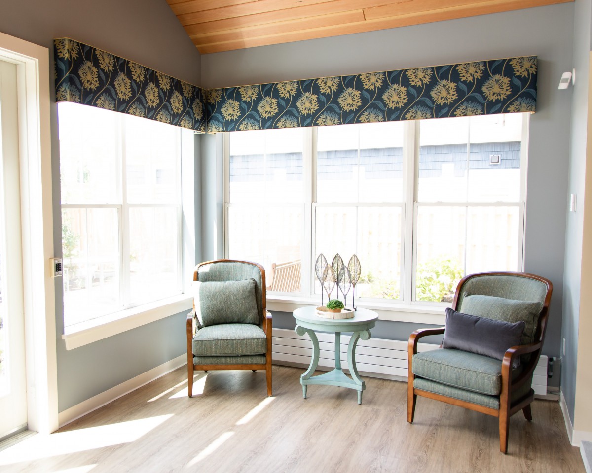A sunlit living room corner with two armchairs and a small coffee table by the window.