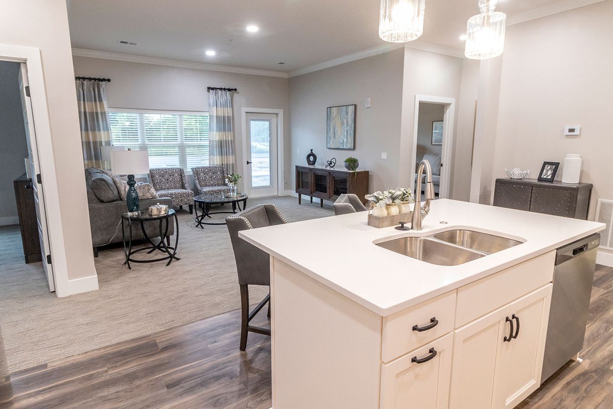 A modern open-plan kitchen and living room with white countertops and contemporary furnishings.
