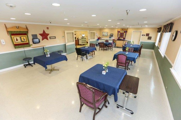 A spacious dining area with neatly arranged tables and chairs, covered in blue tablecloths.