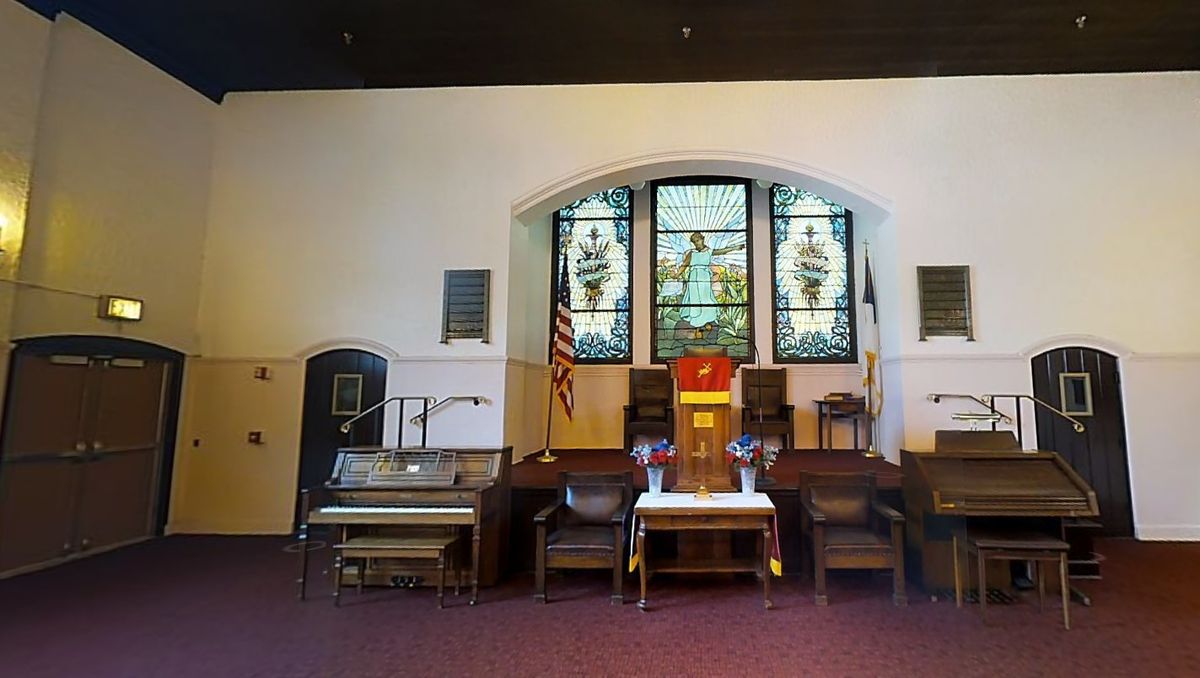 Interior of a church featuring stained glass windows, an altar, and an organ.