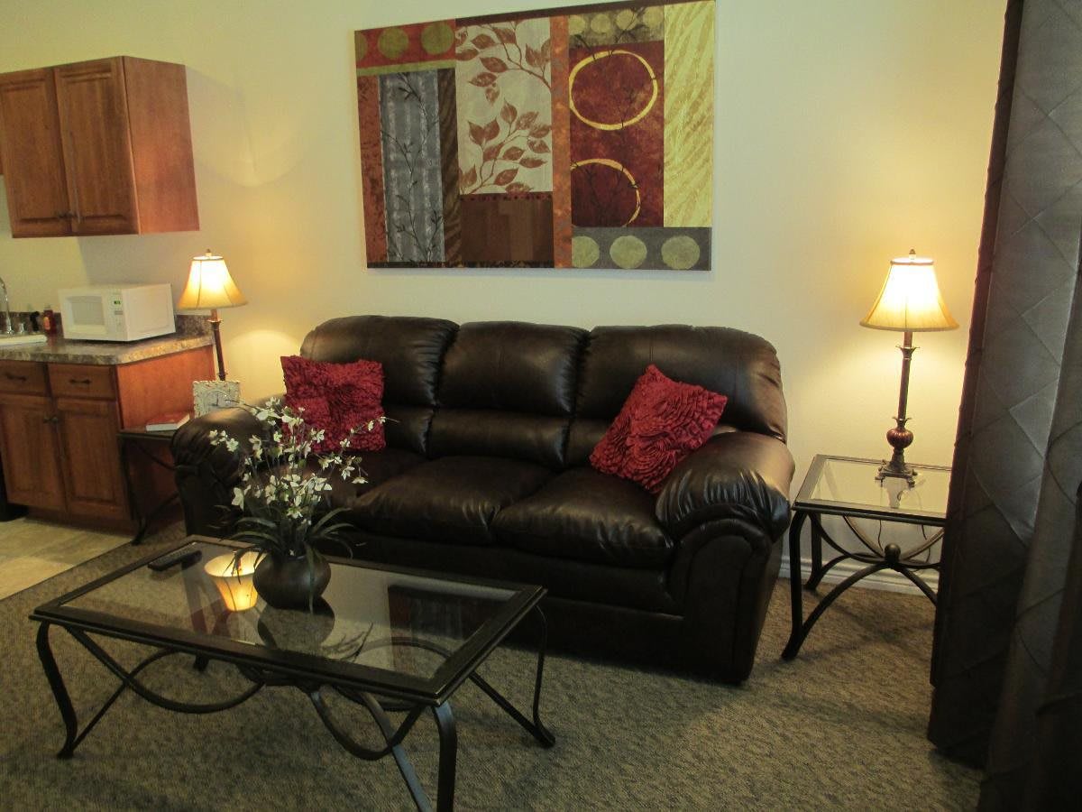 A cozy living room with a leather sofa, glass coffee table, and decorative artwork on the wall.