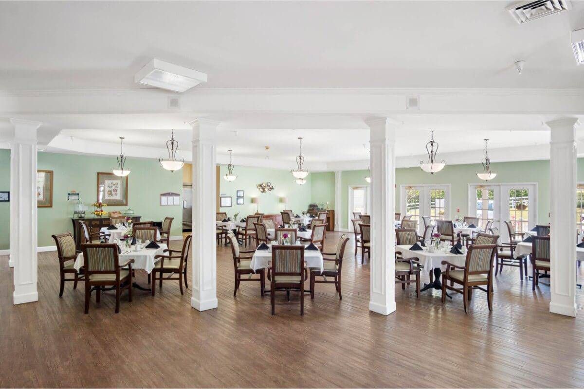 A spacious and elegantly decorated dining room with multiple tables set for guests.