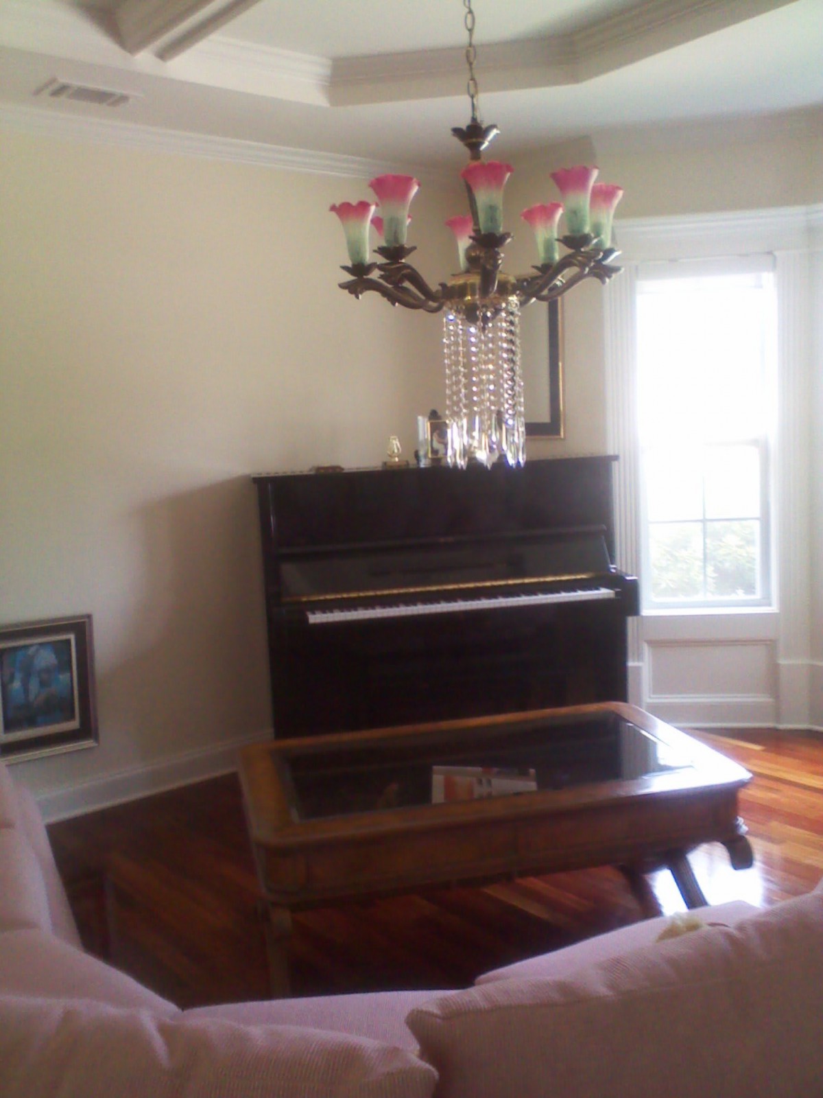 A cozy living room with a piano and chandelier.