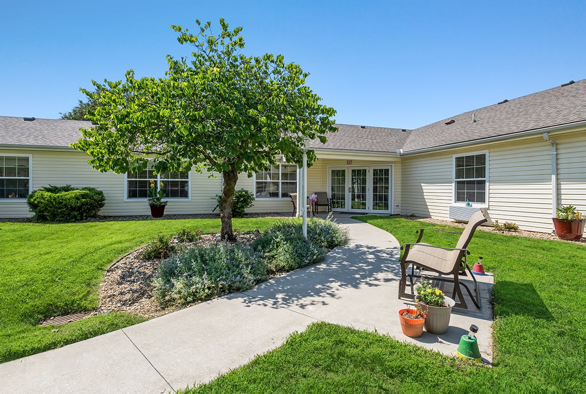 A residential backyard featuring a well-maintained lawn, a garden with shrubs, and a patio area with outdoor seating.