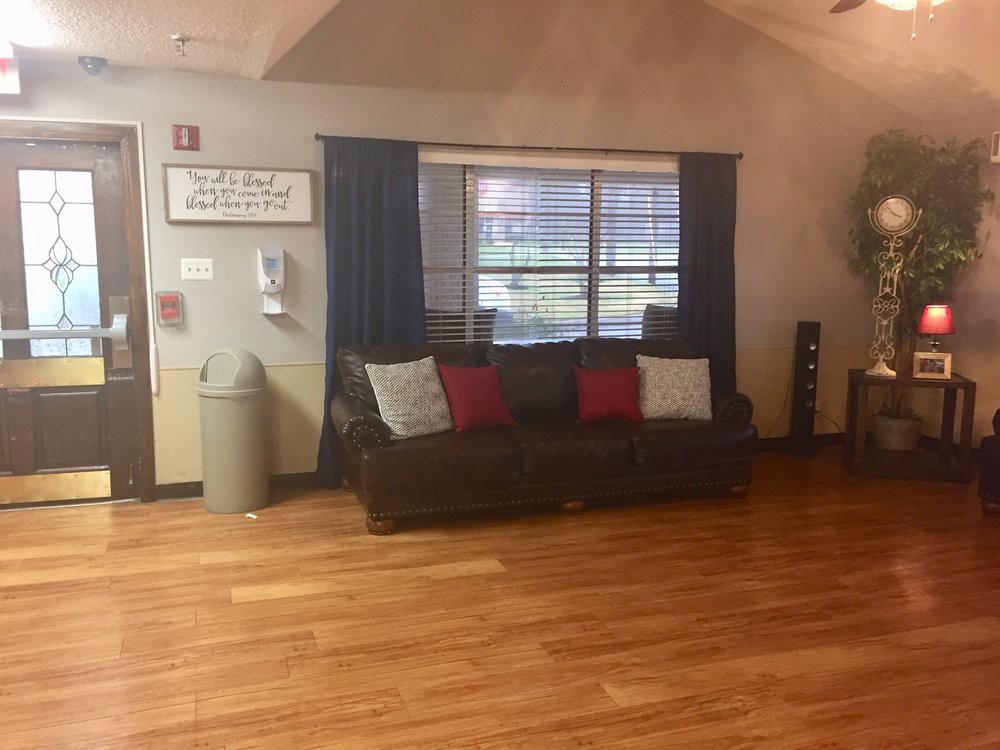 A cozy living room with a brown sofa, colorful pillows, and wooden flooring.