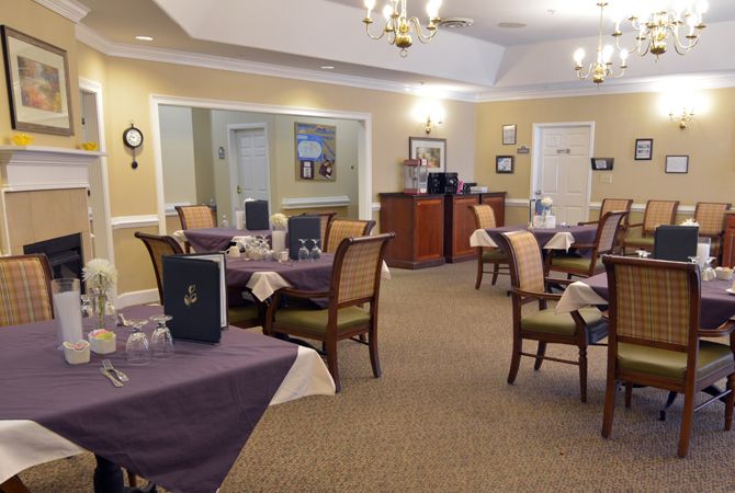 A cozy dining area with neatly arranged tables and chairs, adorned with chandeliers and soft lighting.